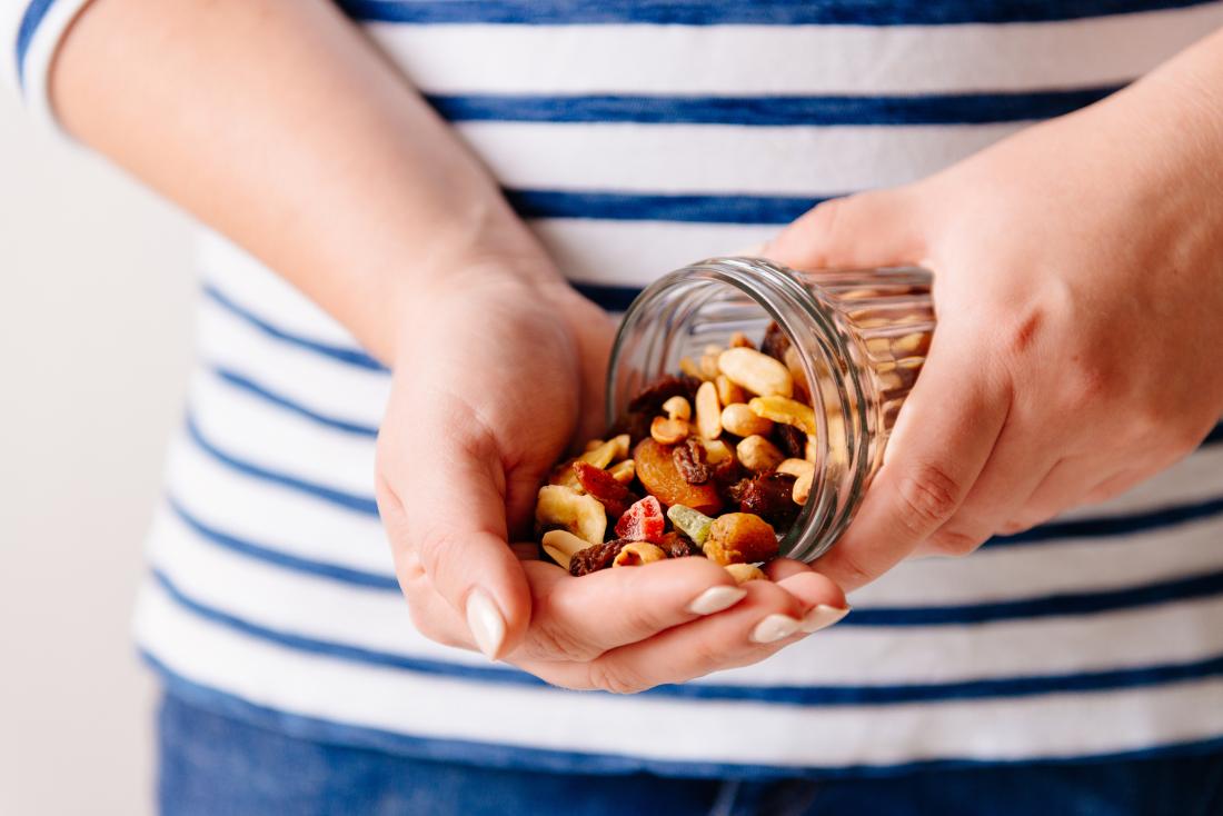 woman pouring nuts and dried fruit into hand