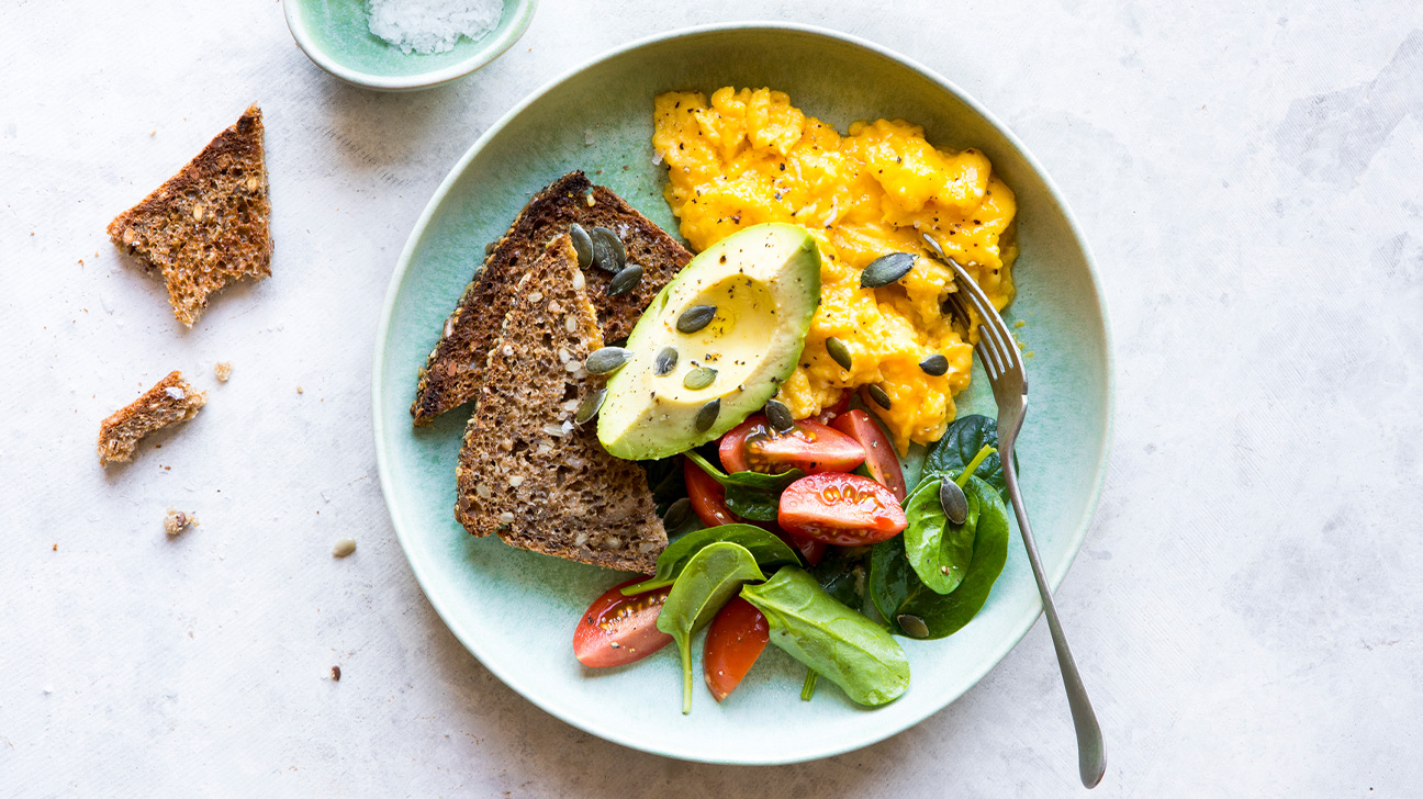 plate with whole-grain toast, eggs, avocado, and fresh salad